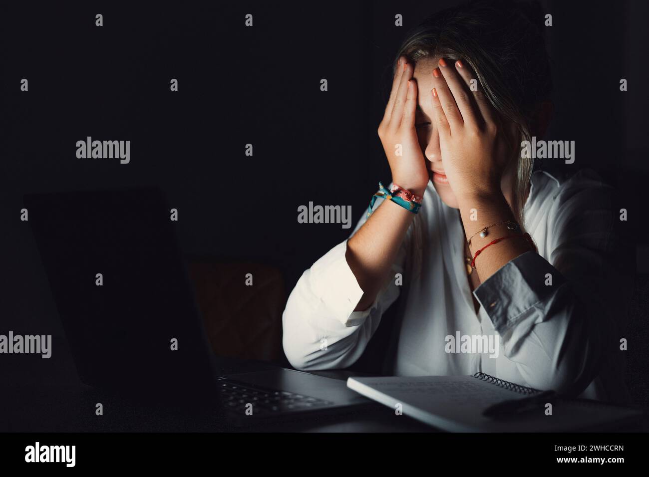 Giovane studente caucasico sopraffatto che tocca la testa, soffre di vista sfocata, massaggiare il ponte nasale alleviando il dolore, sentirsi stanco di lavorare a tarda sera con il computer in ufficio. Foto Stock