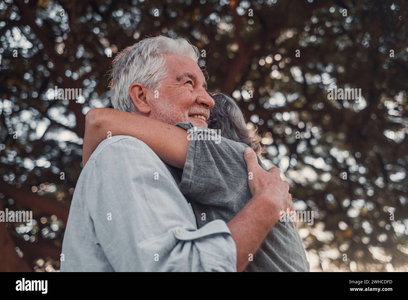 Foto della testa Ritratto ravvicinato donna di mezza età dai capelli grigi felice che si accoccia al marito più anziano sorridente, godendosi un momento tenero al parco. Legare una vecchia coppia di famiglia amorevole che abbraccia e prova felicità. Foto Stock