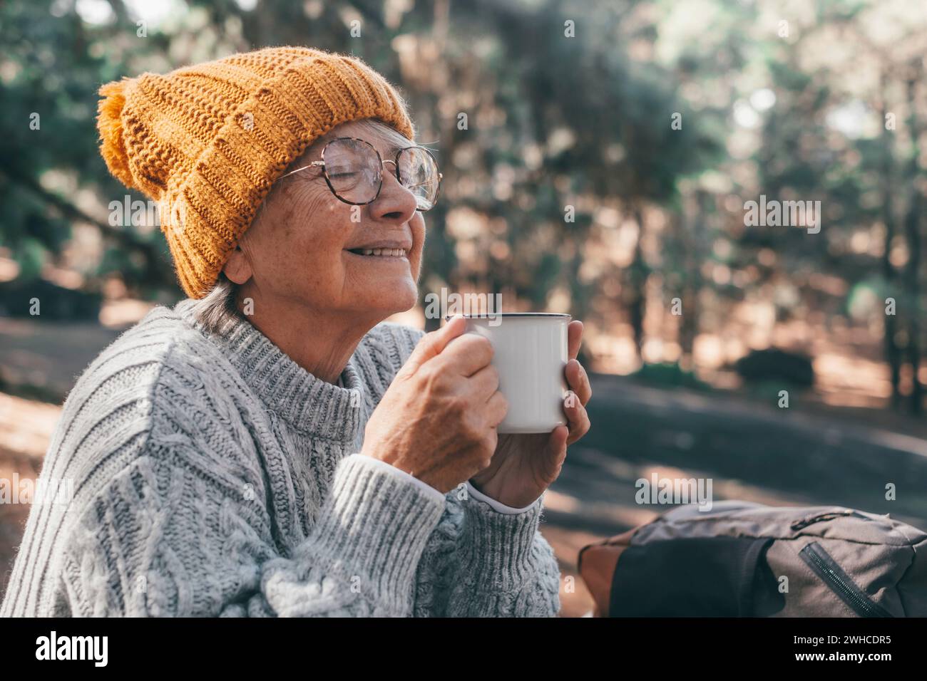 Ritratto, primo piano di una donna di mezza età che si rilassa bevendo un caffè o un tè seduti a tavola nella foresta di montagna in mezzo alla natura. La stagione autunnale si apprezza lo stile di vita Foto Stock