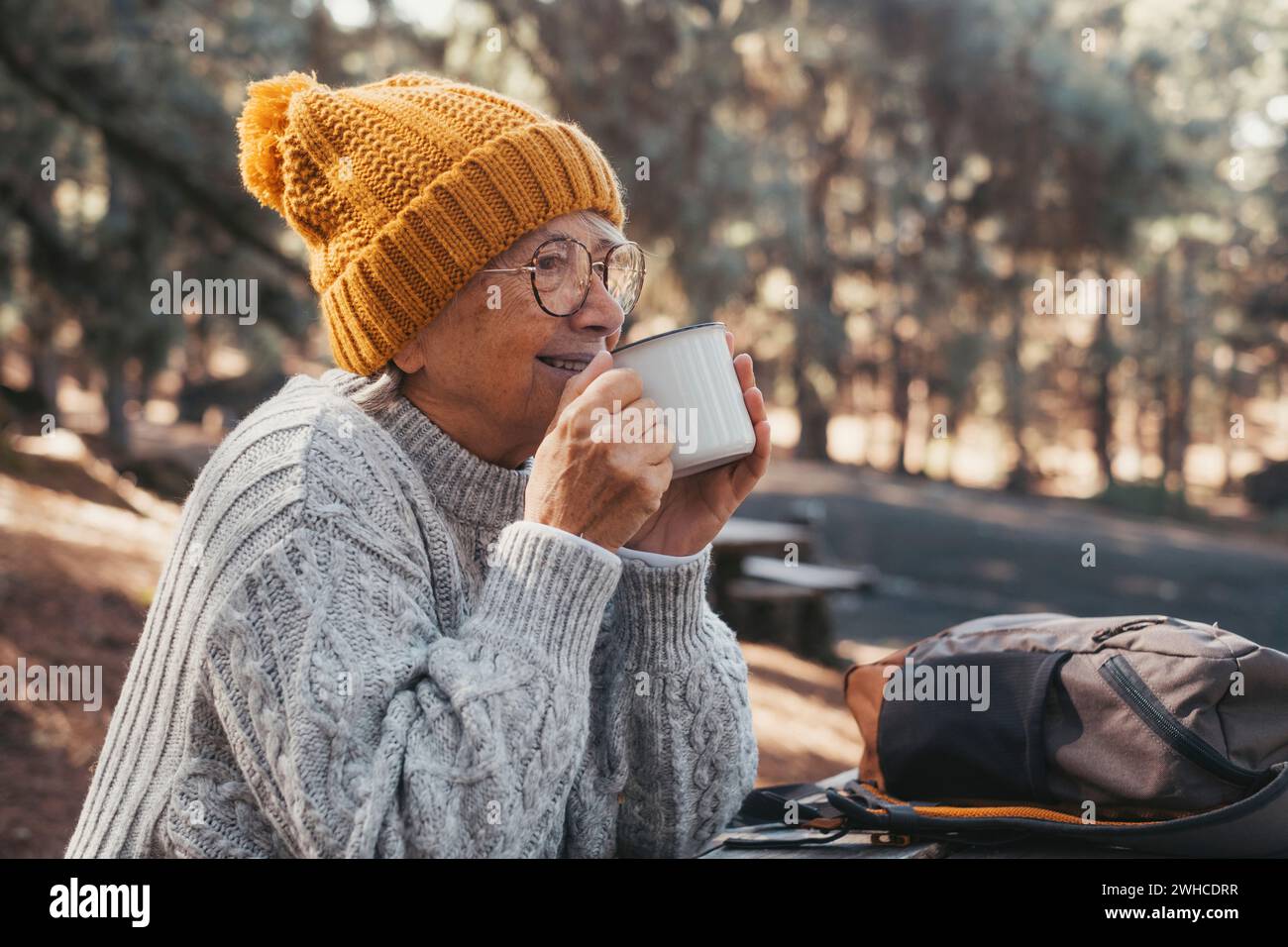 Ritratto, primo piano di una donna di mezza età che si rilassa bevendo un caffè o un tè seduti a tavola nella foresta di montagna in mezzo alla natura. La stagione autunnale si apprezza lo stile di vita Foto Stock