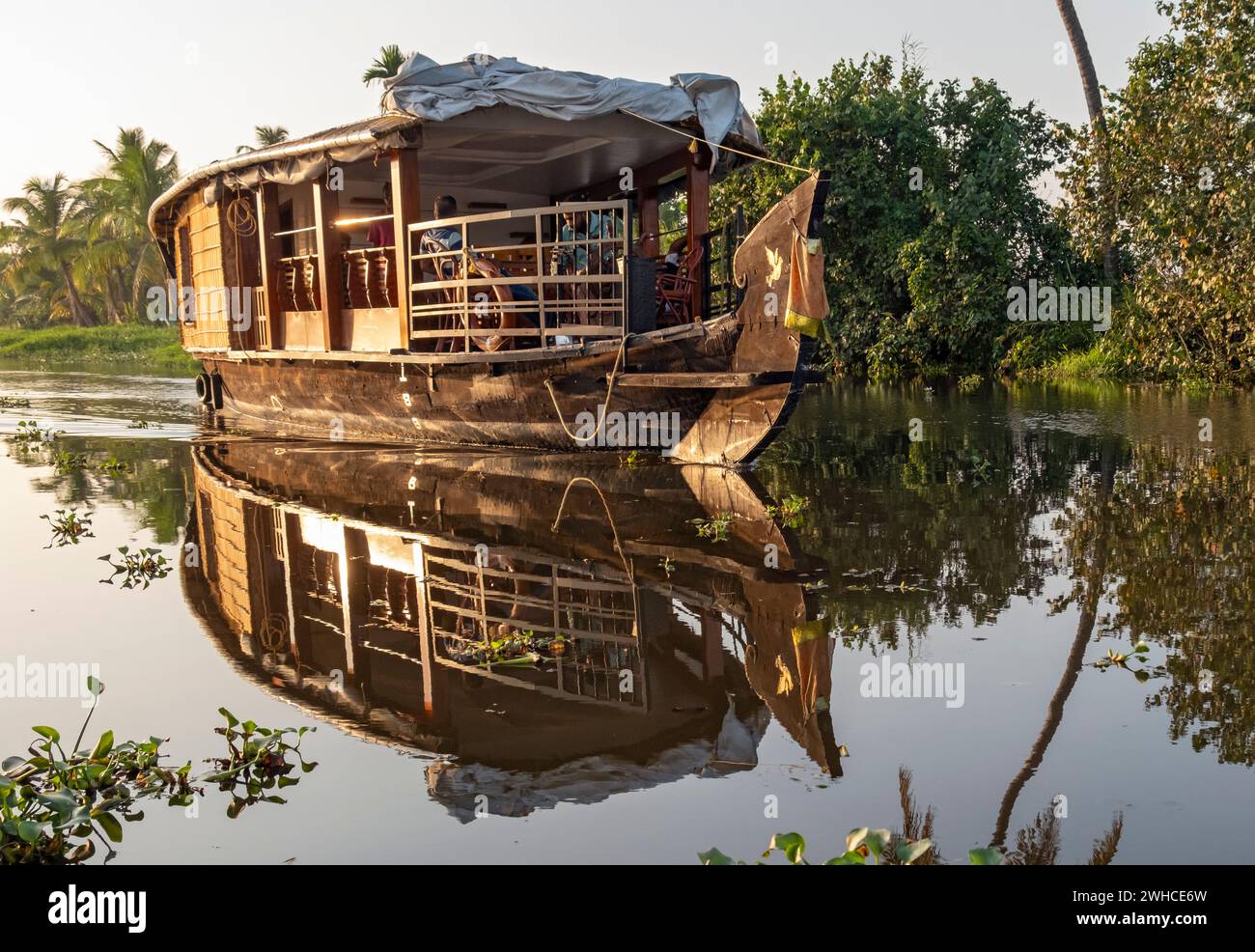 Una tradizionale casa galleggiante naviga lungo i canali vicino a Kumarakom, offrendo un modo unico di esplorare le tranquille backwaters del Kerala, in India Foto Stock