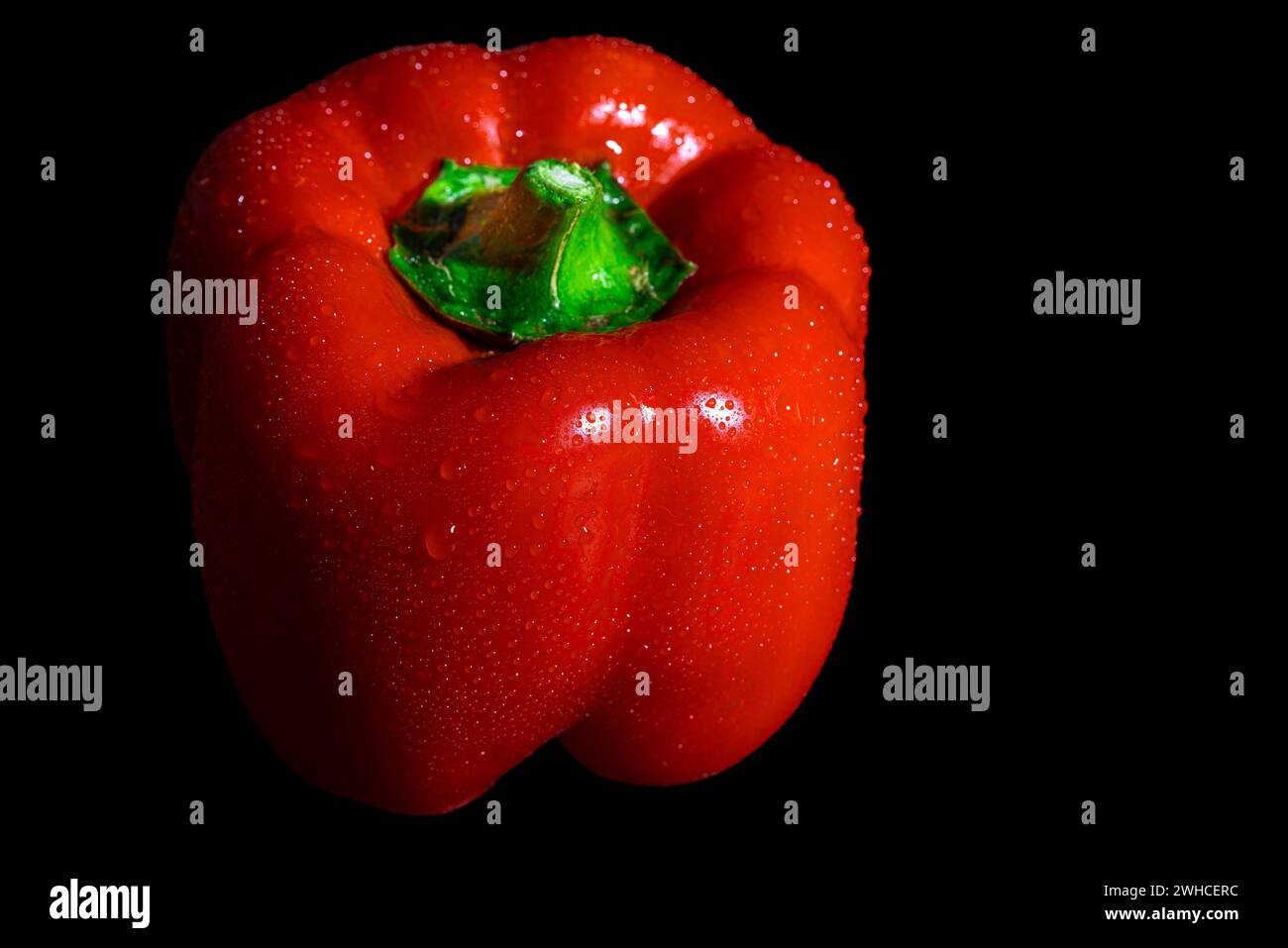 Capsicum rosso con gocce sulla superficie, sfondo scuro Foto Stock