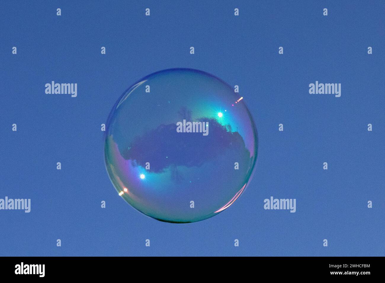 Pellicola colorata con bolle di sapone di acqua saponata con riflesso davanti al cielo blu Foto Stock