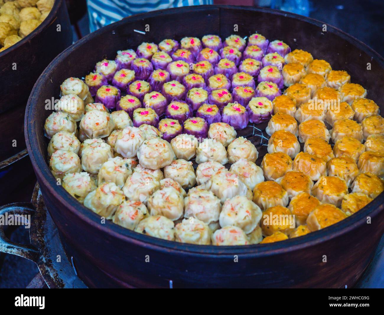 Colorato dim sum al vapore, gnocchi cinesi in una vaporiera in legno. Venditore di gnocchi nel mercato asiatico del cibo di strada in Malesia e Taiwan Foto Stock