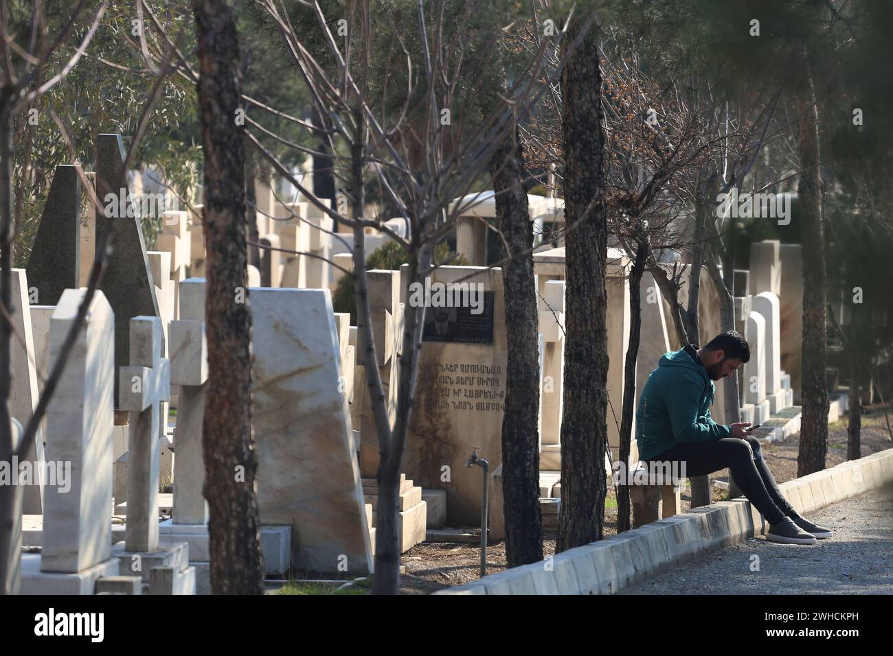Teheran, Iran. 8 febbraio 2024. Un uomo cristiano iraniano si trova vicino alle tombe del cimitero di Nor Burastan, che è il principale cimitero armeno fondato nel 1974 dalla St Stephen Chapel nel sud-est di Teheran. Gli armeni iraniani (armeni persiani) sono iraniani di etnia armena che possono parlare l'armeno come loro prima lingua. Le stime del loro numero in Iran vanno da 70.000 a 500.000. Le aree con un'alta concentrazione di queste includono Tabriz, Teheran, Salmas e il quartiere Jolfa (Nor Jugha) di Isfahan. (Credit Image: © Rouzbeh Fouladi/ZUMA Press Wire) SOLO PER USO EDITORIALE! Non per Commercial US Foto Stock