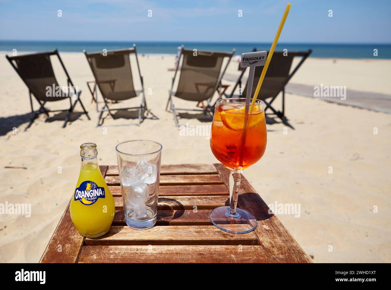 Una bottiglia di Orangina, un bicchiere con cubetti di ghiaccio e un bicchiere di Aperol Spritz con una paglia in un bar sulla spiaggia a Soulac-sur-Mer, Gironde Foto Stock