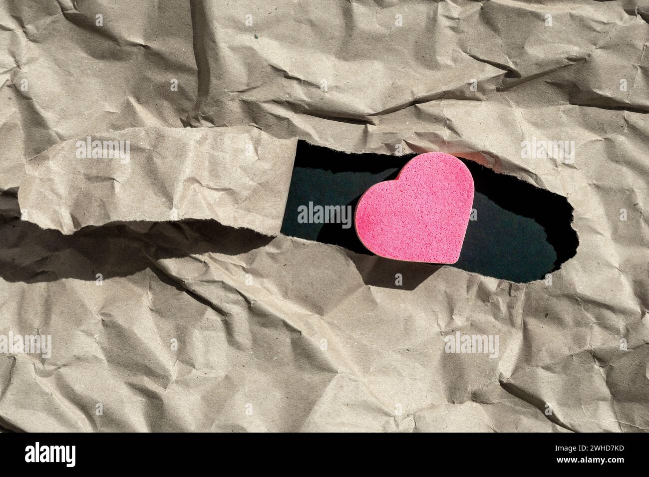 cuore sul foro in carta stropicciato. Simbolo di amore infelice. Concetto di unità sociale Foto Stock