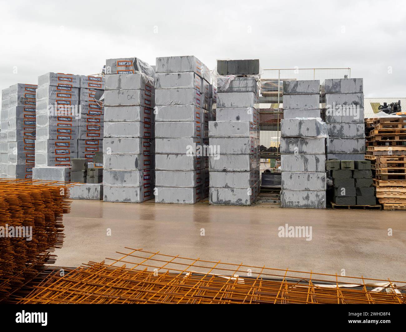 Una grande quantità di blocchi di costruzione Thermalite in cantieri commerciali di costruttori con rete di rinforzo in metallo in primo piano Foto Stock