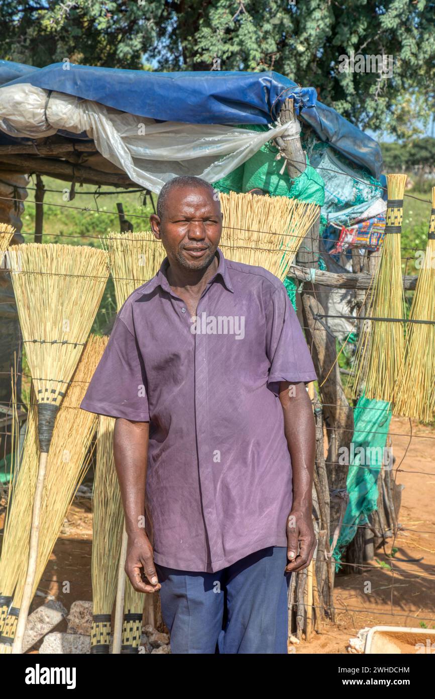 vecchio imprenditore africano che produce scope, venditore ambulante con un piccolo chiosco sul lato dell'autostrada Foto Stock
