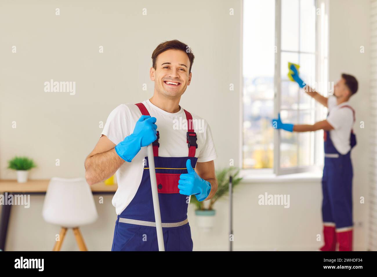 Custode felice in uniforme da un servizio di pulizia professionale che guarda la fotocamera. Foto Stock
