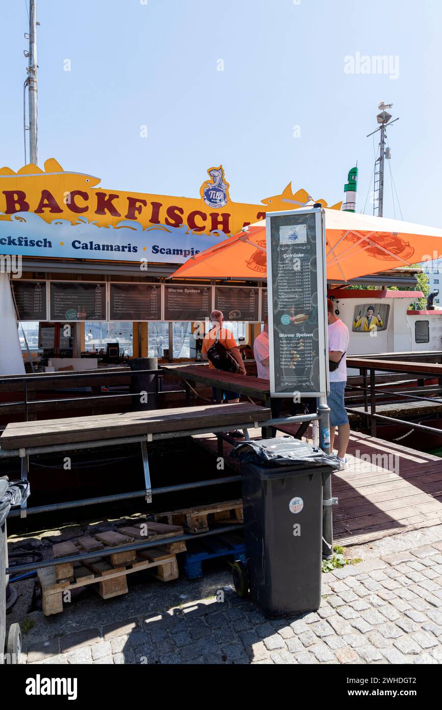 Vista dalla passeggiata sull'Alter Strom su una barca da pesca che vende pesce fritto a Warnemünde, nella città anseatica di Rostock, sulla costa del Mar Baltico, Mecklenbur Foto Stock
