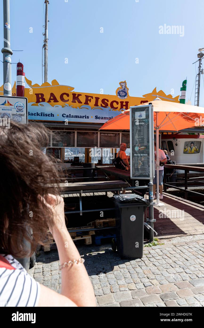 Vista dalla passeggiata sull'Alter Strom su un peschereccio che vende pesce fritto a Warnemünde, nella città anseatica di Rostock, sulla costa del Mar Baltico, sul Meclemburgo-Pomerania Occidentale, in Germania, in Europa Foto Stock