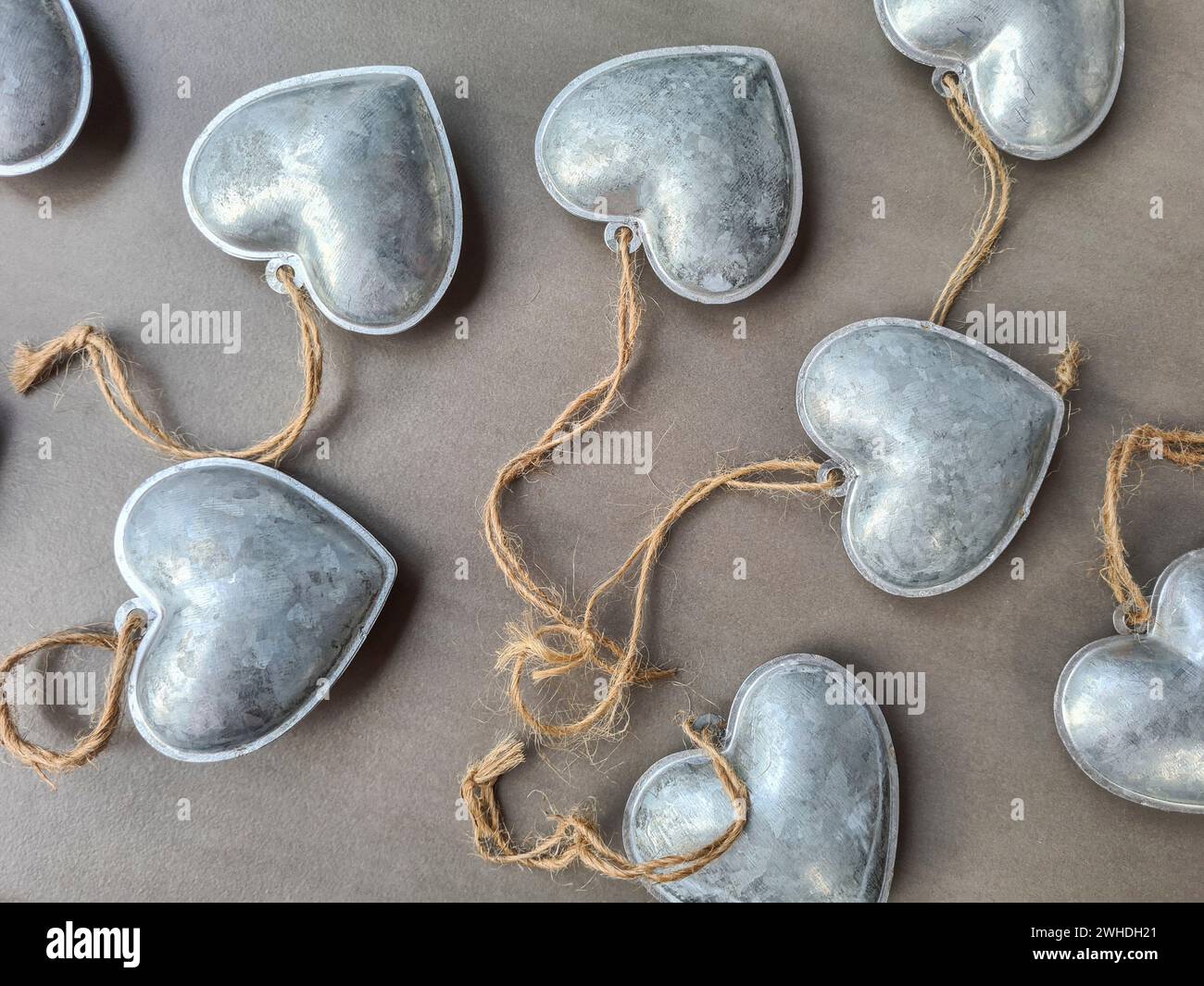 I ciondoli decorativi in argento a forma di cuore si trovano su uno sfondo grigio per festeggiare l'amore a San Valentino Foto Stock