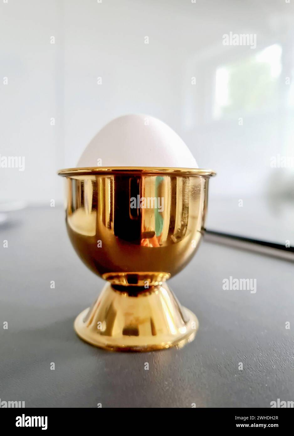 Un uovo bianco sodo in una tazza d'uovo dorato per colazione a Pasqua Foto Stock