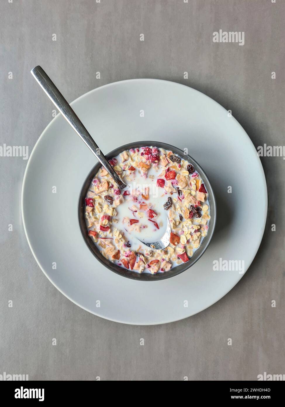 Muesli con latte in una ciotola per colazione, muesli di frutta con cereali e frutta, cucchiaio Foto Stock
