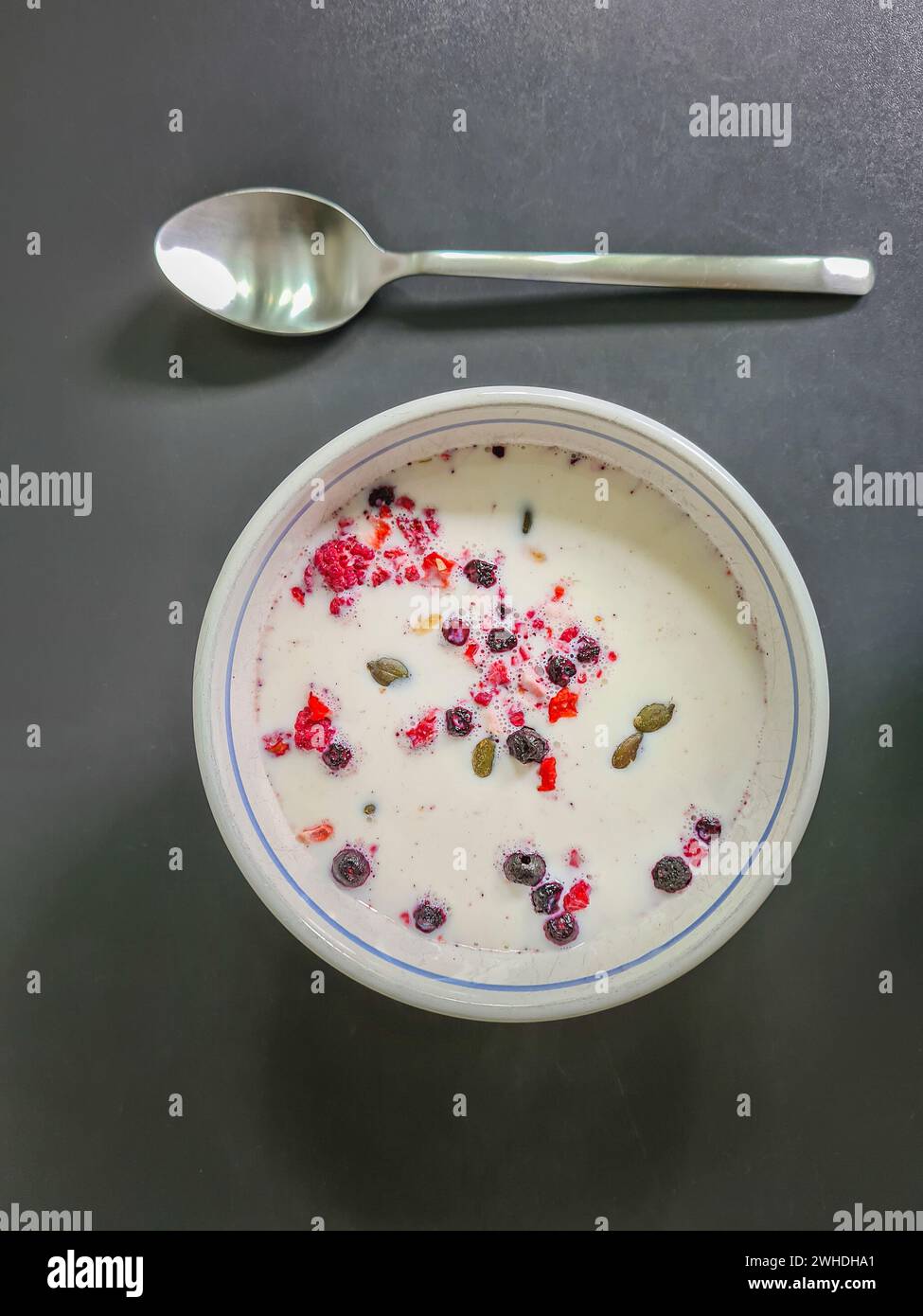 Muesli con latte in una ciotola per colazione, muesli di frutta con cereali e frutta, cucchiaio Foto Stock