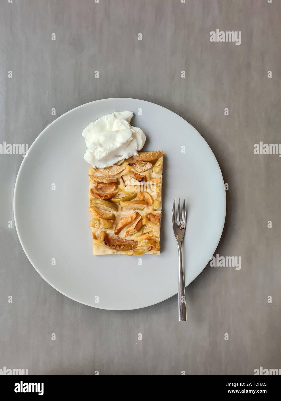 Una fetta di torta di mele con panna servita su un piatto con una forchetta Foto Stock