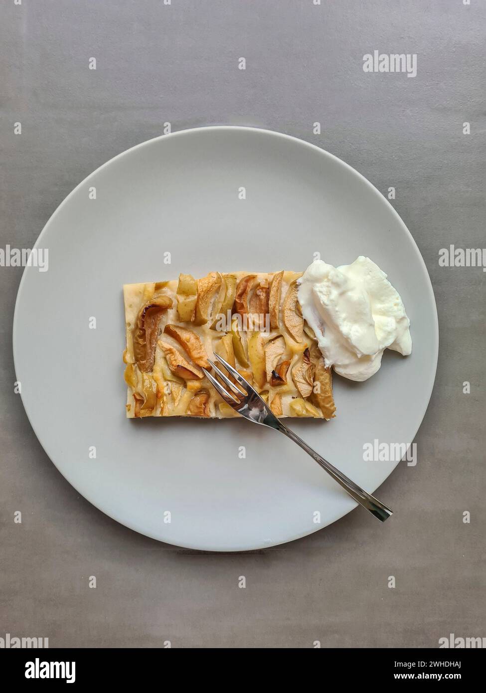 Una fetta di torta di mele con panna servita su un piatto con una forchetta Foto Stock