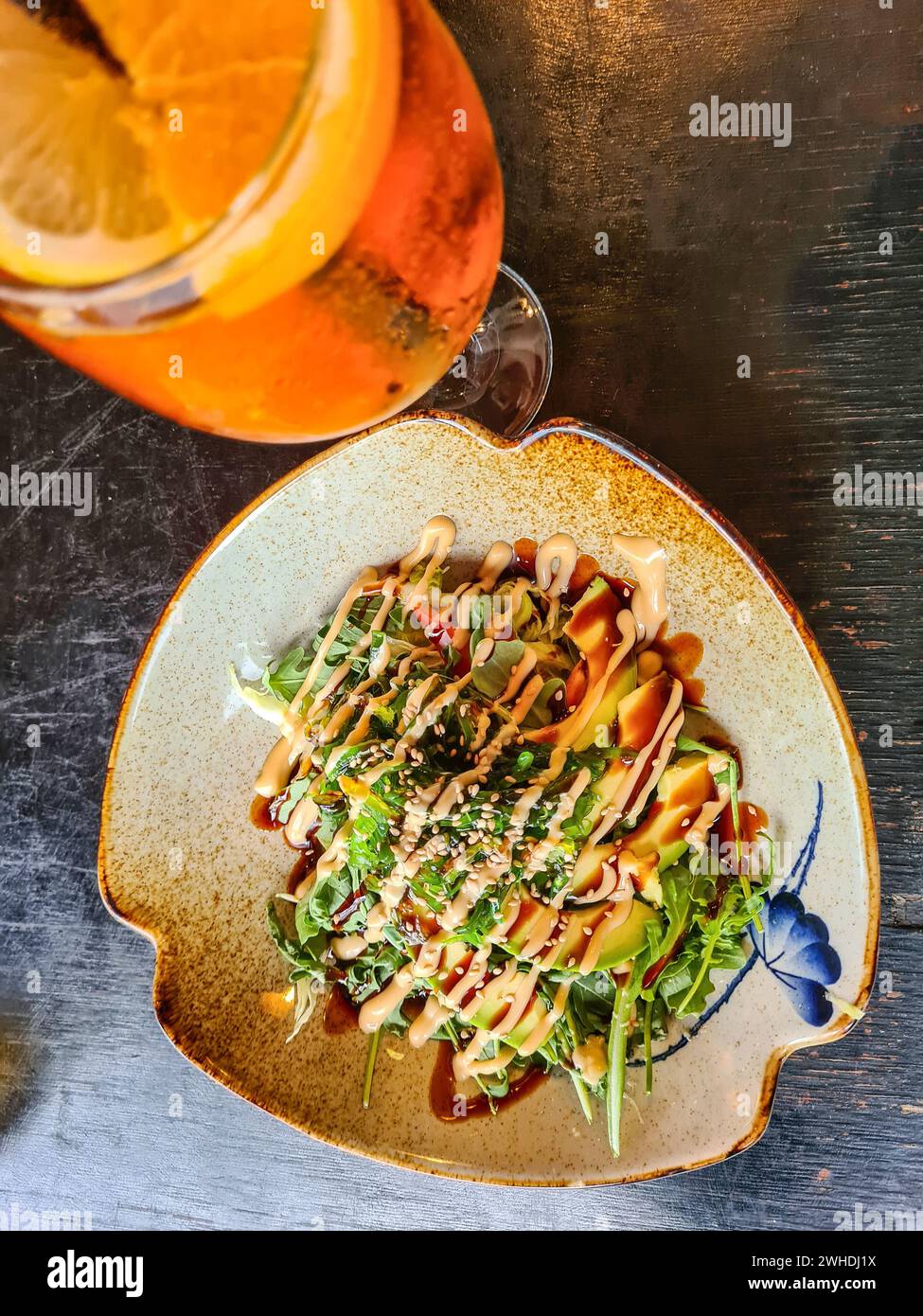 Una bevanda estiva alcolica di colore arancio e un'insalata di avocado con semi di sesamo nel ristorante Foto Stock