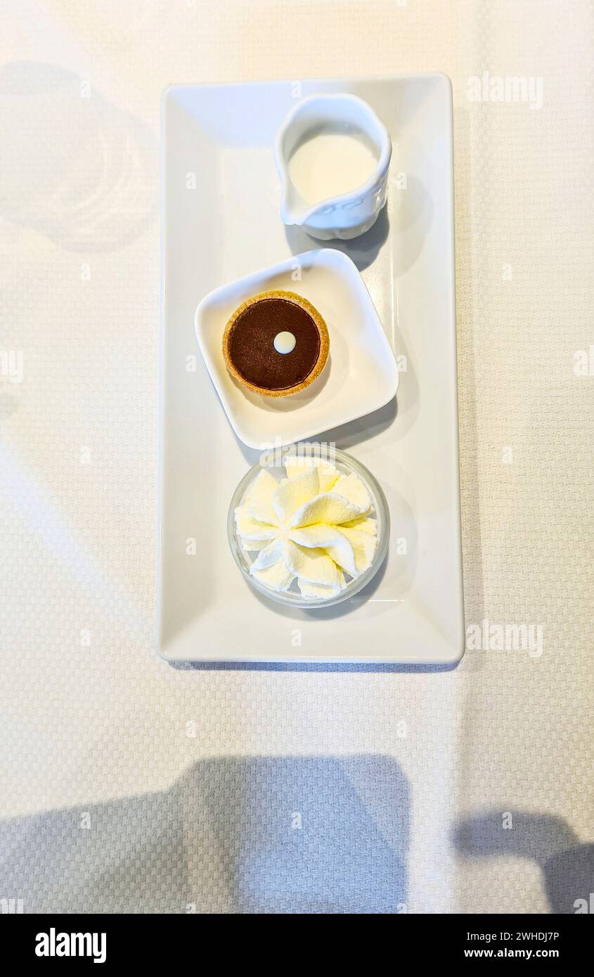 Un posto con tartine di cioccolato e panna e una caraffa di latte per dessert su un piatto di porcellana bianca Foto Stock