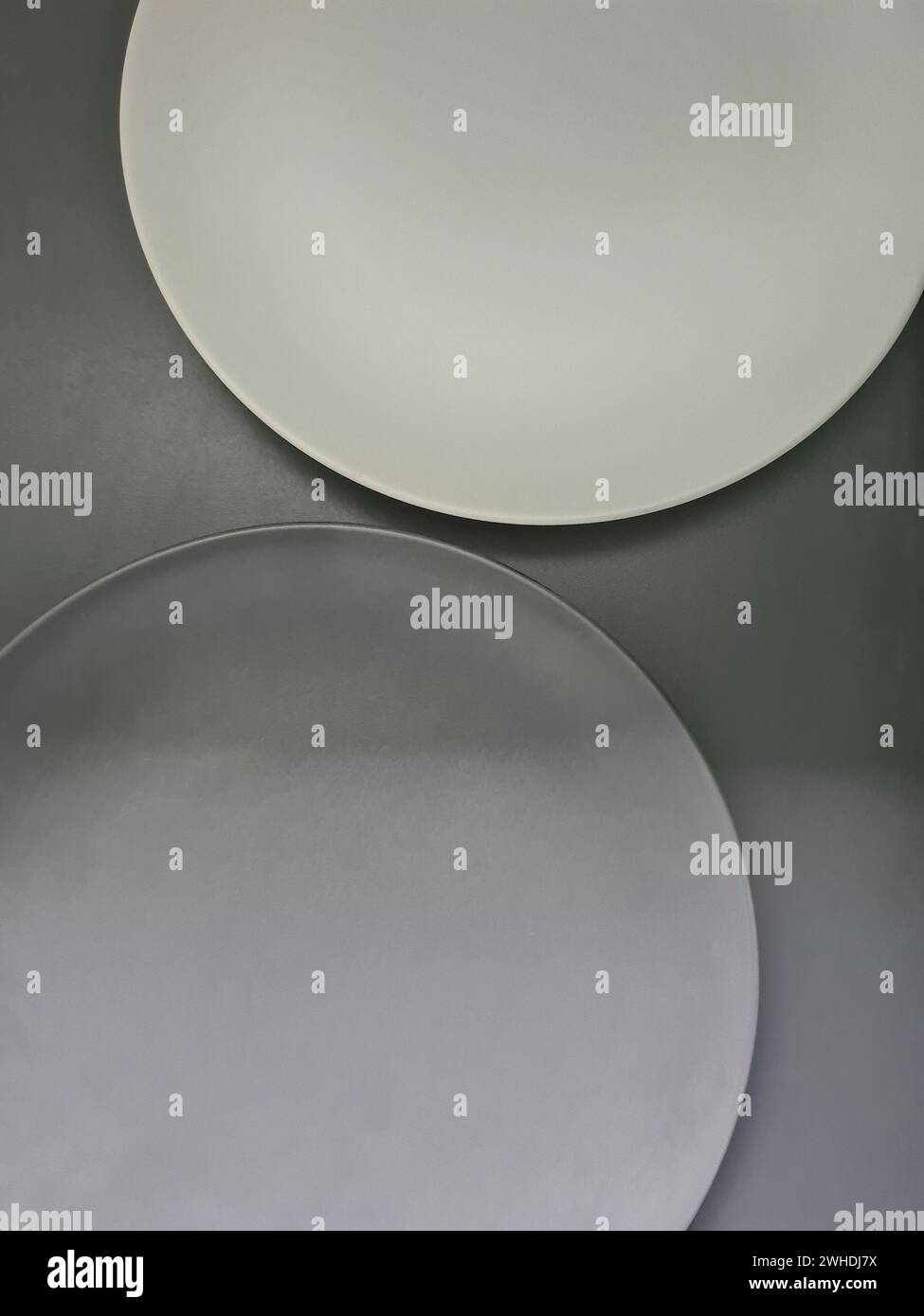 un piatto bianco e un piatto grigio su sfondo grigio sul tema dei contrasti e del minimalismo Foto Stock