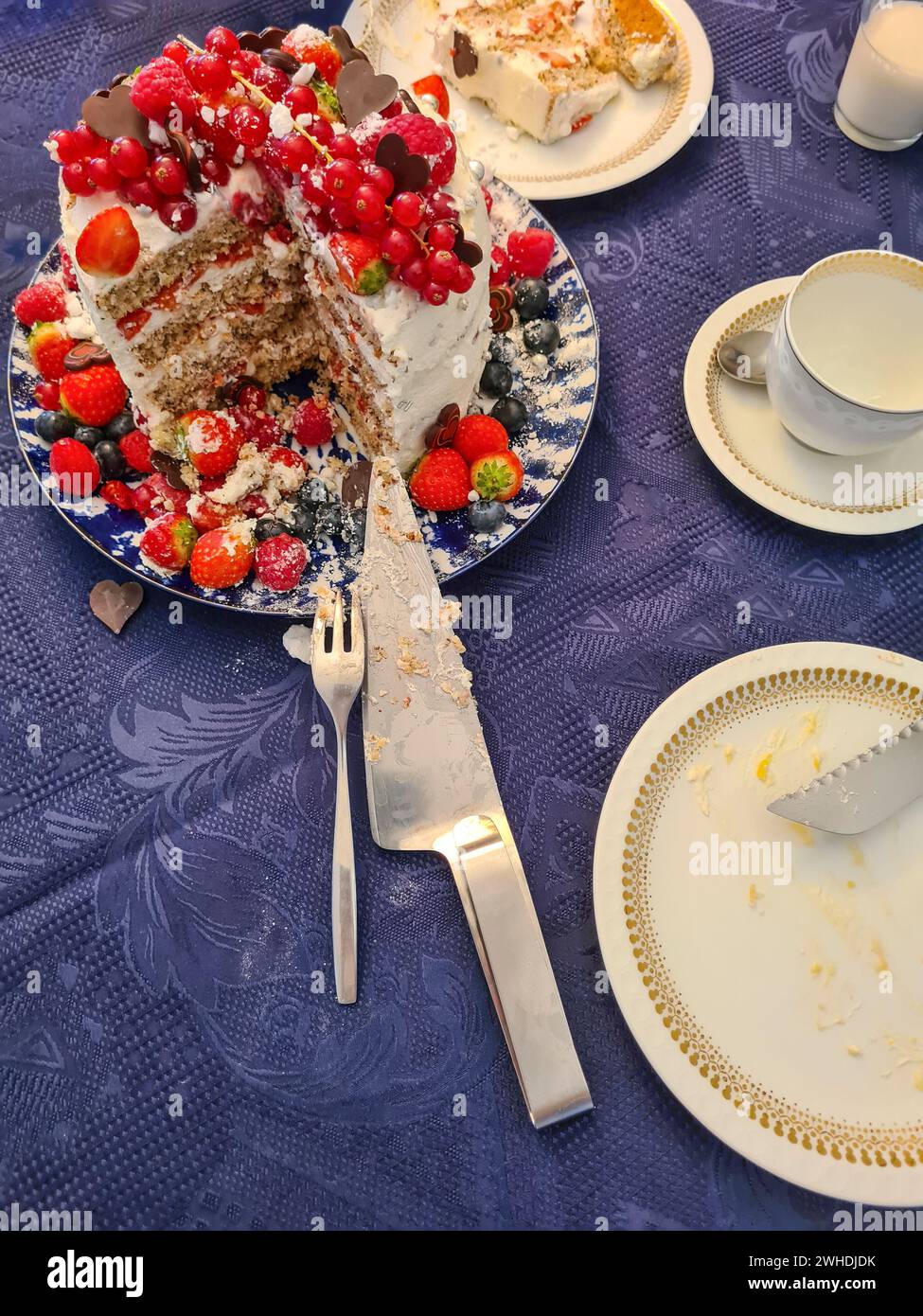 Una torta cremosa natalizia con frutta come fragole, lamponi, ribes e mirtilli mentre la decorazione viene tagliata e mostra la sezione trasversale della torta e i suoi strati individuali Foto Stock