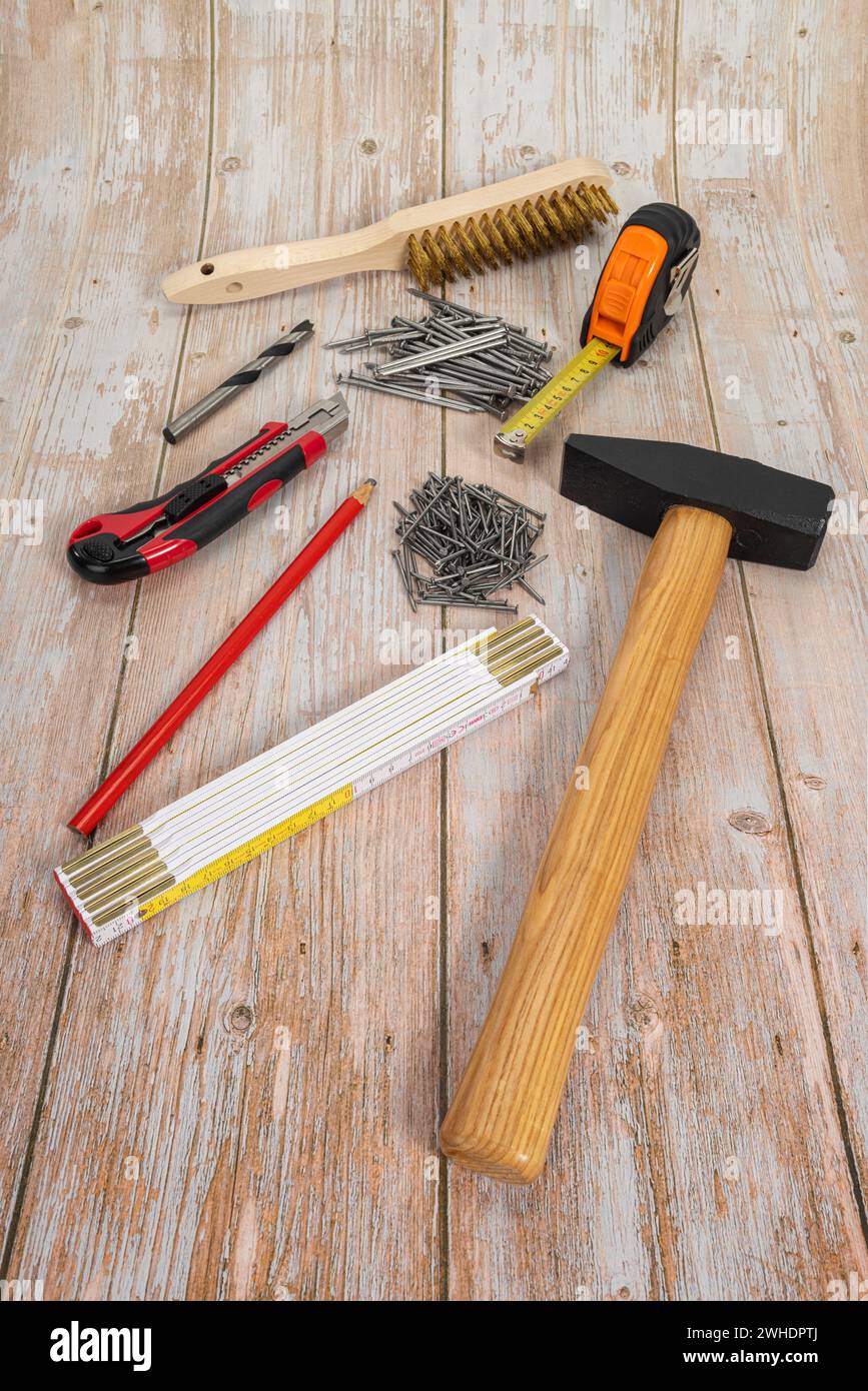 Martello da fabbro 1000 g, chiodi in acciaio, metro pieghevole, matita da falegname, coltello da taglio, trapano per legno, spazzola metallica manuale in ottone, metro a nastro, fondo in legno, Foto Stock