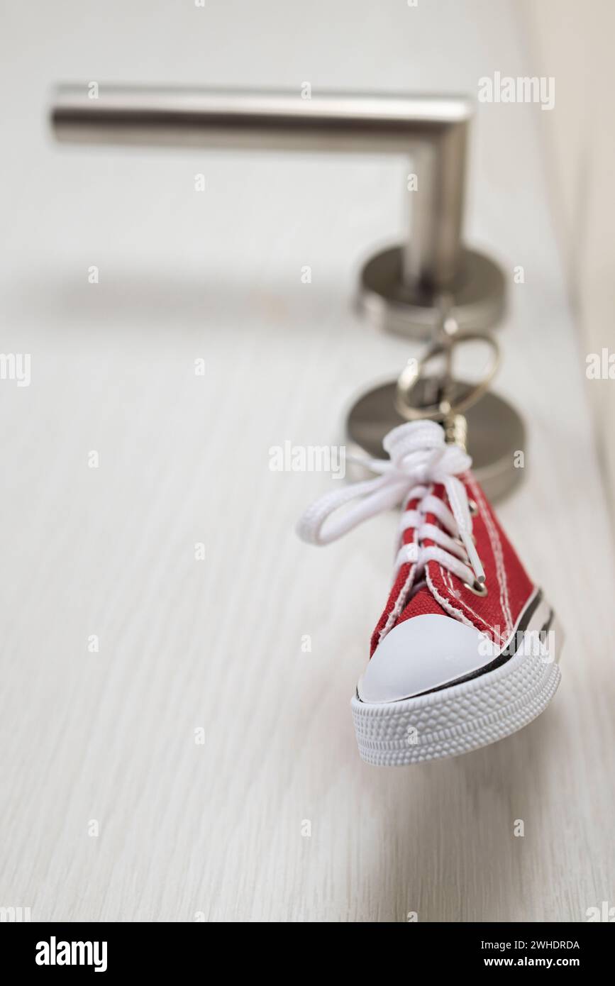 Chiave della camera con portachiavi in miniatura per sneaker bloccato nella serratura della porta, porta della stanza dei bambini, Foto Stock