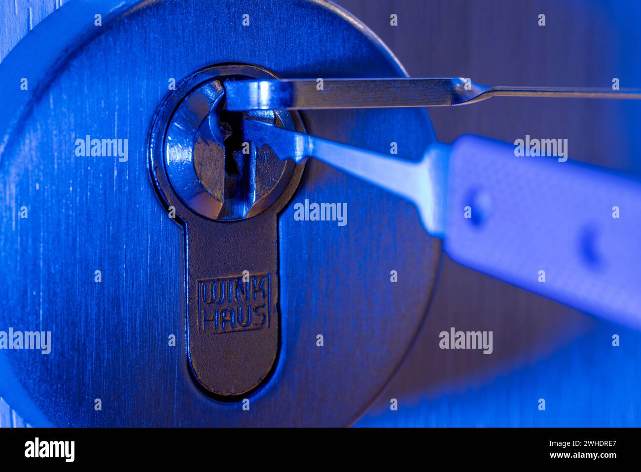 Il ladro apre la serratura a cilindro con lo strumento di bloccaggio, dettaglio, luce blu, immagine simbolica, furto domestico, Foto Stock