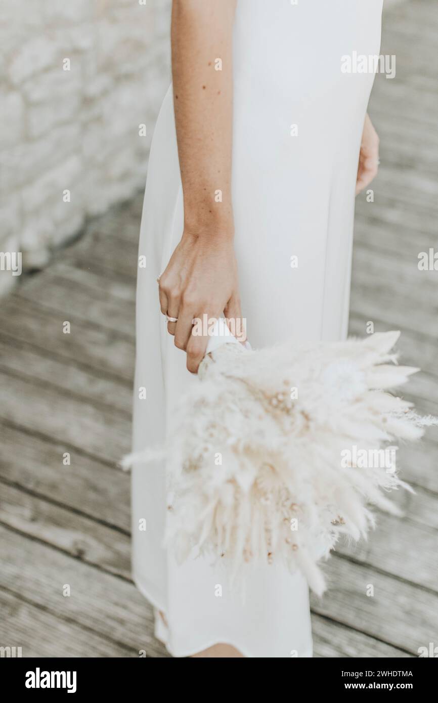 La sposa tiene in mano casualmente un bouquet nuziale di fiori secchi e pampas Foto Stock