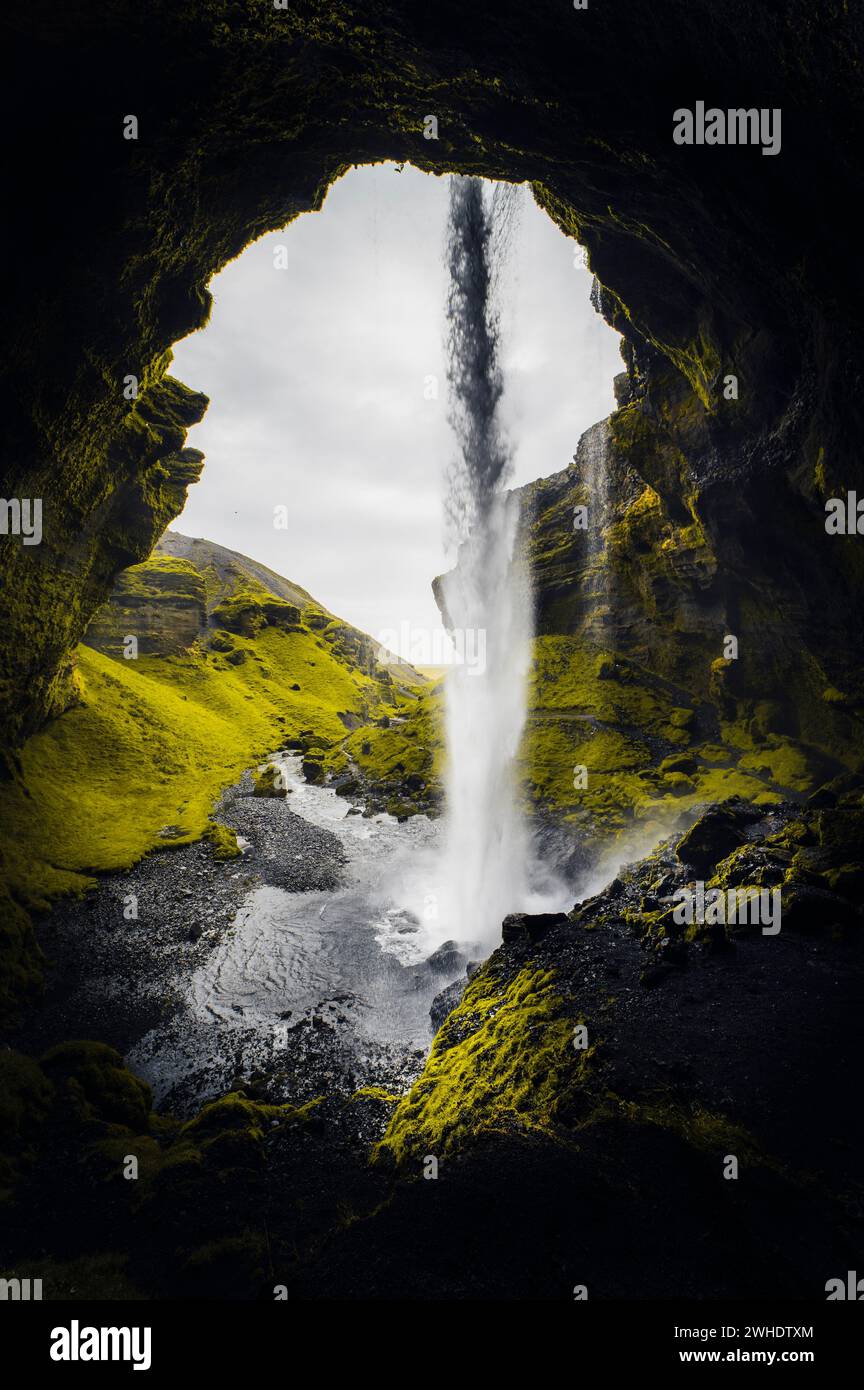 Cascata Kvernufoss in Islanda con arco di roccia e rocce coperte di muschio, vista dalla cascata nella gola Foto Stock