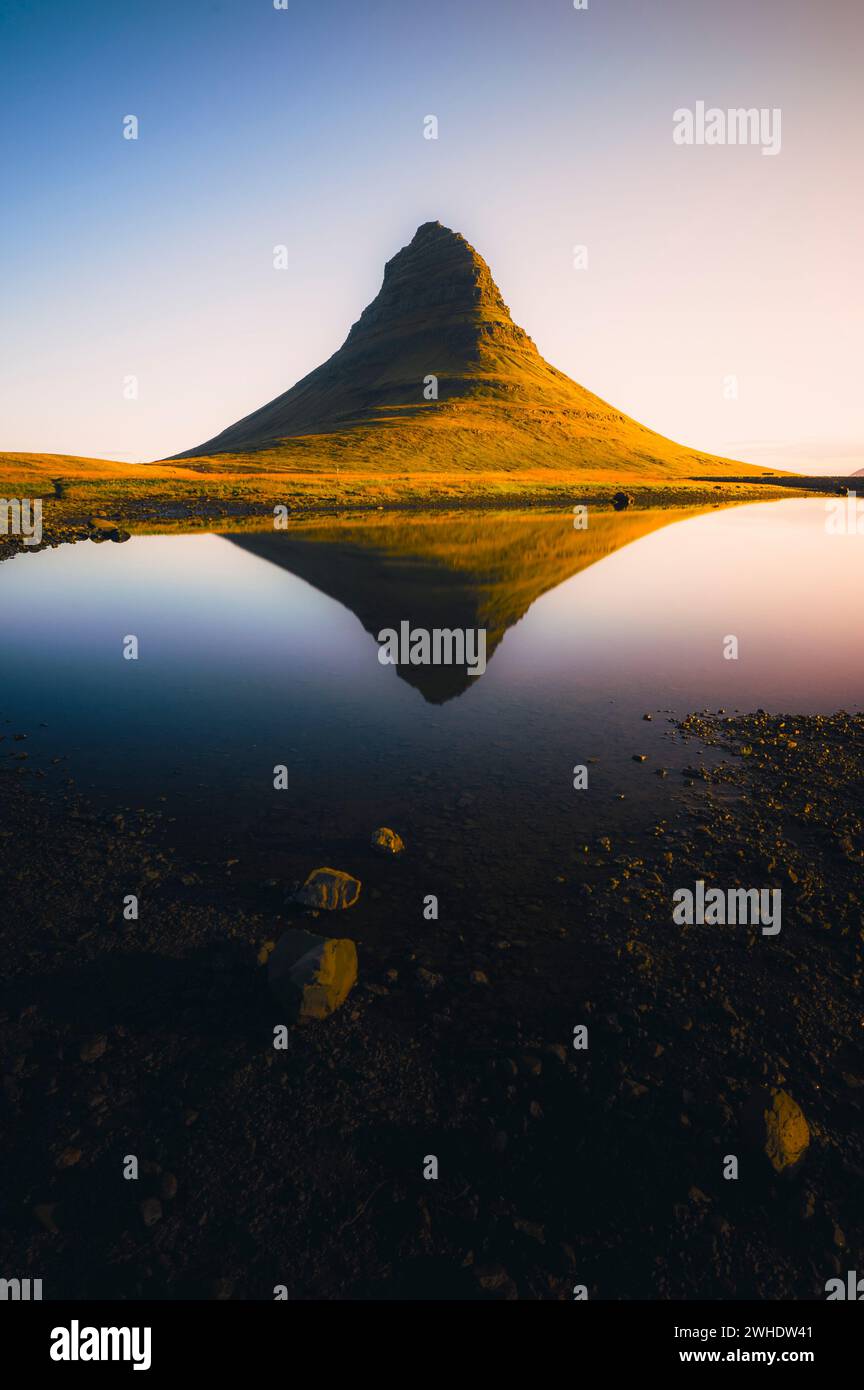 Monte Kirkjufell all'alba sulla penisola di Snaefellsnes in Islanda con Kirkjufellsfoss in primo piano. Riflesso di Kirkjufell nell'acqua Foto Stock