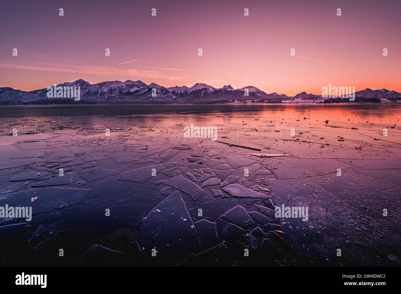 Tramonto sull'Hopfensee ghiacciato con calotte di ghiaccio in primo piano e montagne sullo sfondo, Hopfen am SEE, Ostallgäu, Allgäu, Svevia, Baviera, Foto Stock