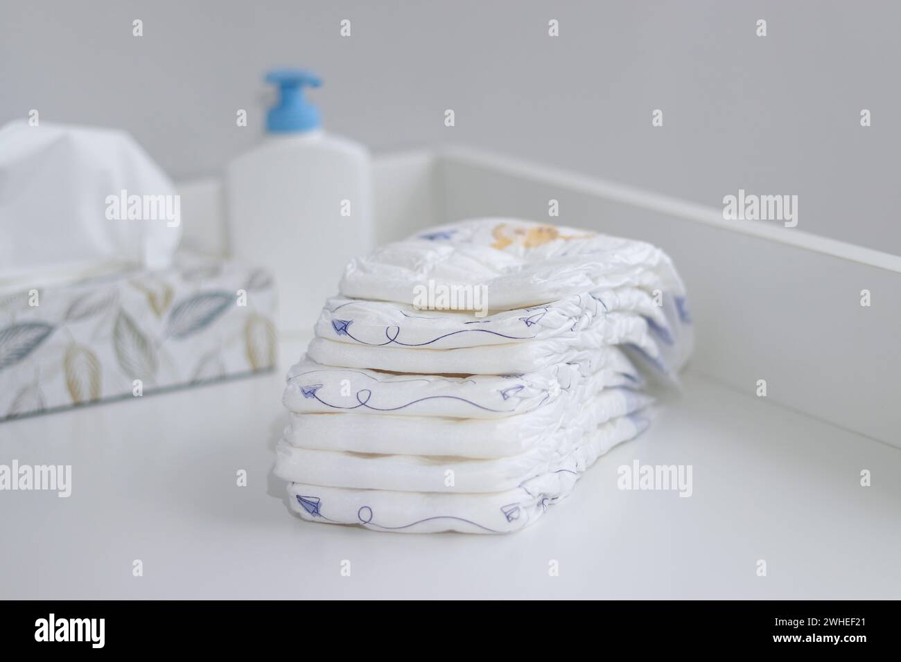 Una pila di pannolini e accessori per bambini sul fasciatoio bianco, nella sala infermieri Foto Stock