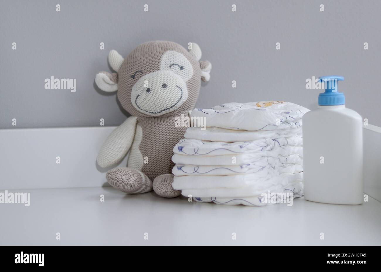 Una pila di pannolini, animali di peluche e articoli per bambini su fasciatoio bianco e sala infermieristica Foto Stock