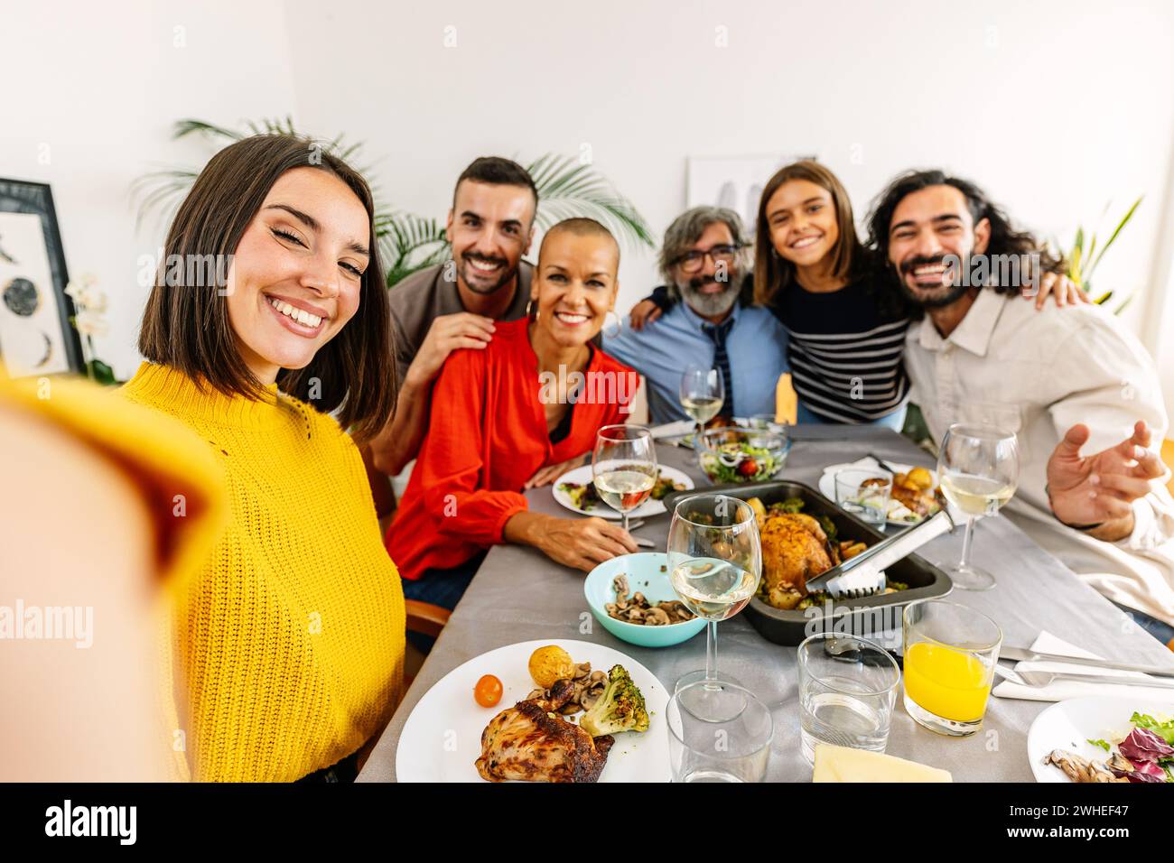 Gruppo di famiglie multigenerazionali che si godono una cena e fanno selfie insieme Foto Stock