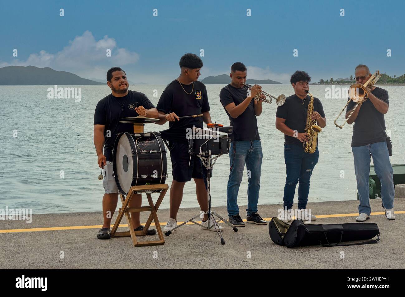 Costa Rica, Puntarenas - 22 luglio 20.23: Closep di cinque jazz band maschili che suonano sul molo sotto il cielo blu. L'acqua del Golfo di Nicoya nel retro. Foto Stock