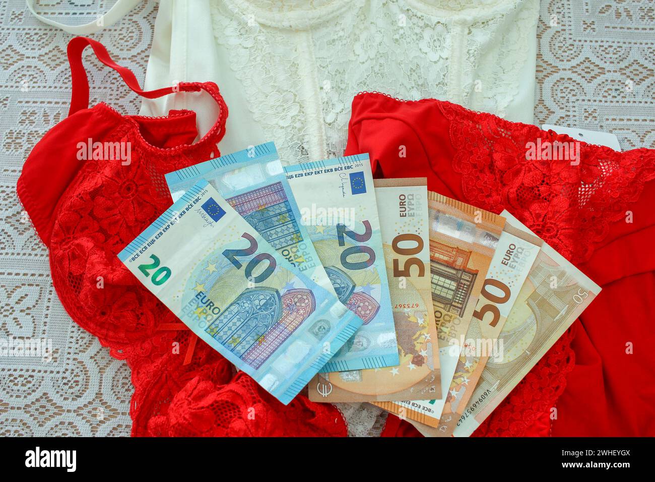 A significare spese per San Valentino, una composizione presenta lingerie rosse abbinate a euro, che riflettono l'investimento finanziario in gestur romantico Foto Stock