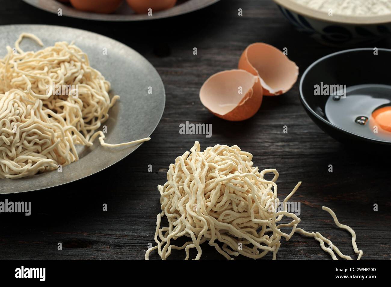 Tagliatelle di uova crude asiatiche fatte in casa nella preparazione su un tavolo di legno Foto Stock