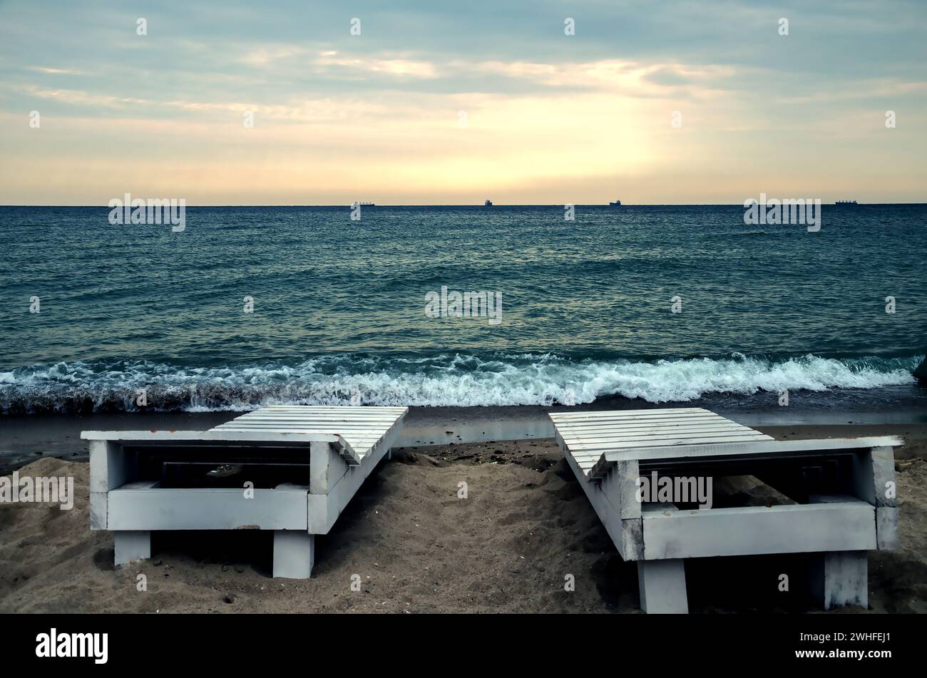 Calda serata estiva con sedie a sdraio, onde spumeggianti e il cielo luminoso sul Mar Nero Foto Stock