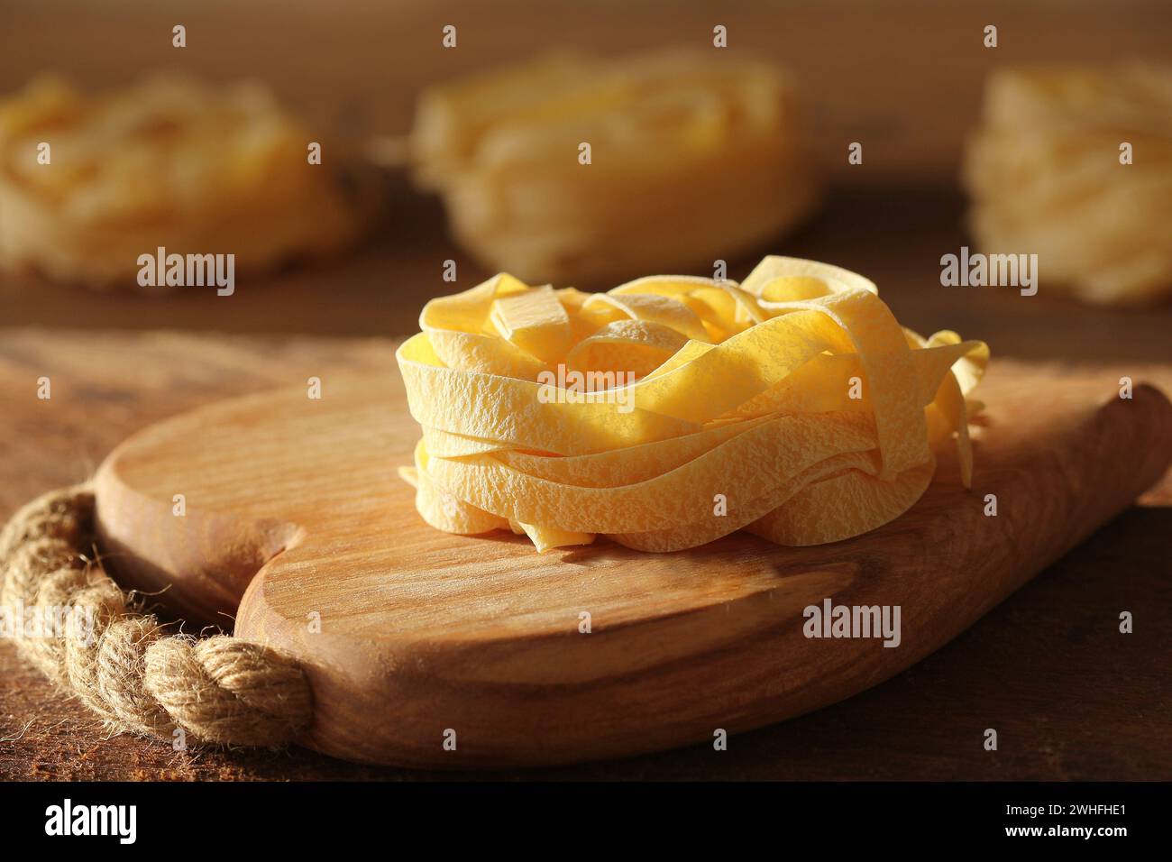 Tagliatelle di pasta italiana cruda su tagliere in legno Foto Stock
