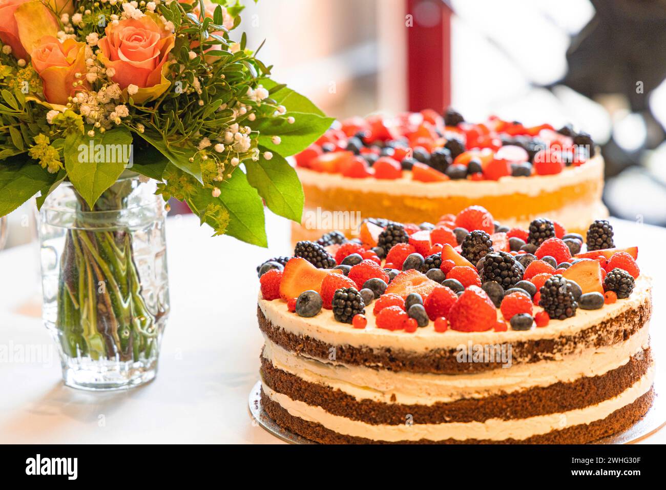 Gustose torte di frutti di bosco e un bouquet di fiori su un tavolo Foto Stock