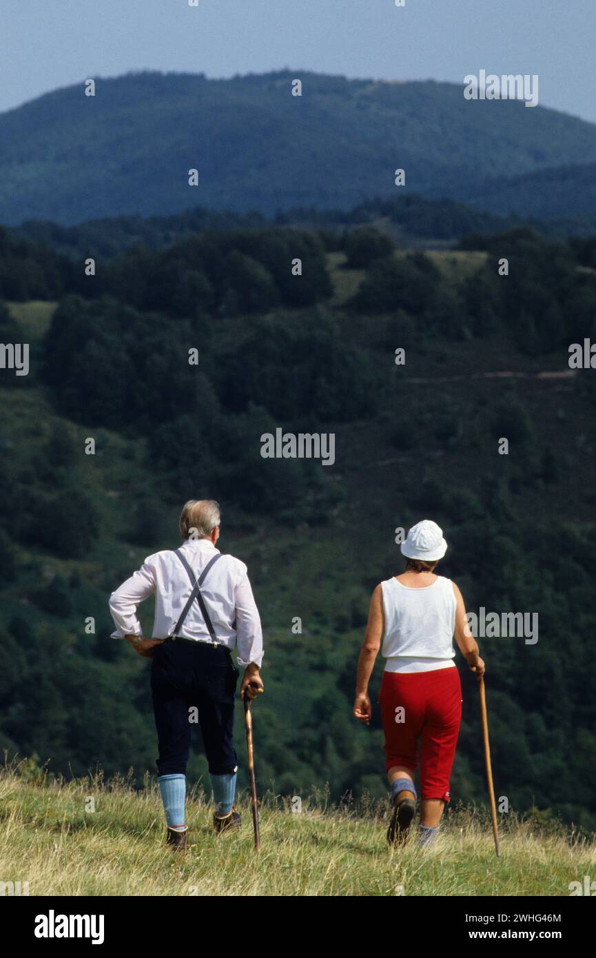 coppia senior francese che cammina all'aperto, sfondo di grenn moutain Foto Stock