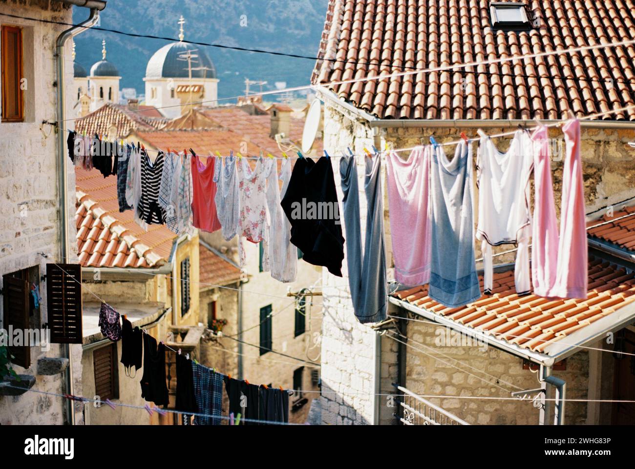 Biancheria multicolore appesa su corde tra vecchie case. Cattaro, Montenegro Foto Stock