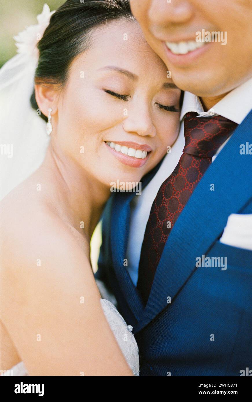 La sposa abbraccia lo sposo, appoggiando la testa sulla spalla. Verticale Foto Stock