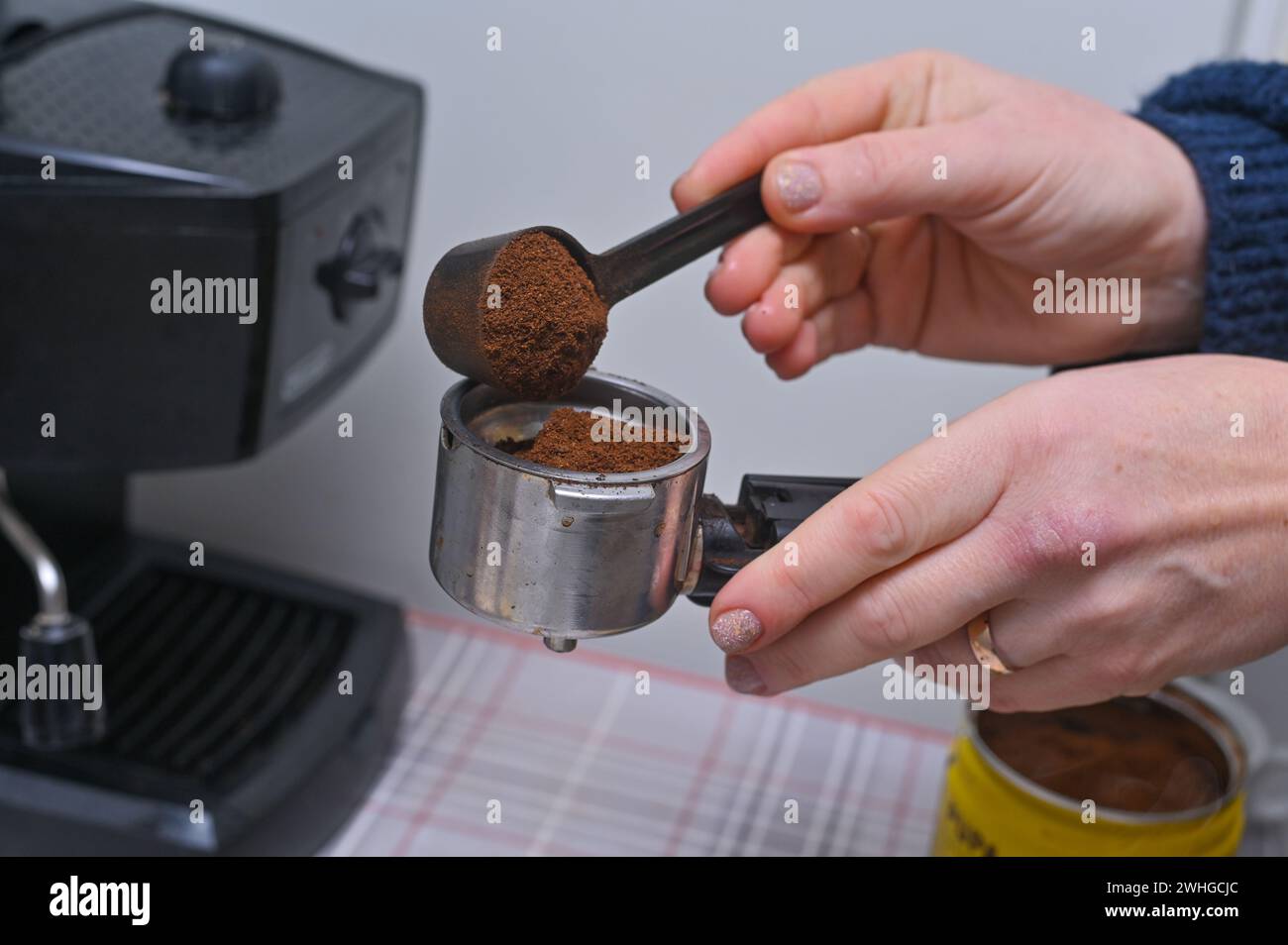 le mani delle donne versano il caffè nel portafiltro della macchina da caffè. primo piano Foto Stock