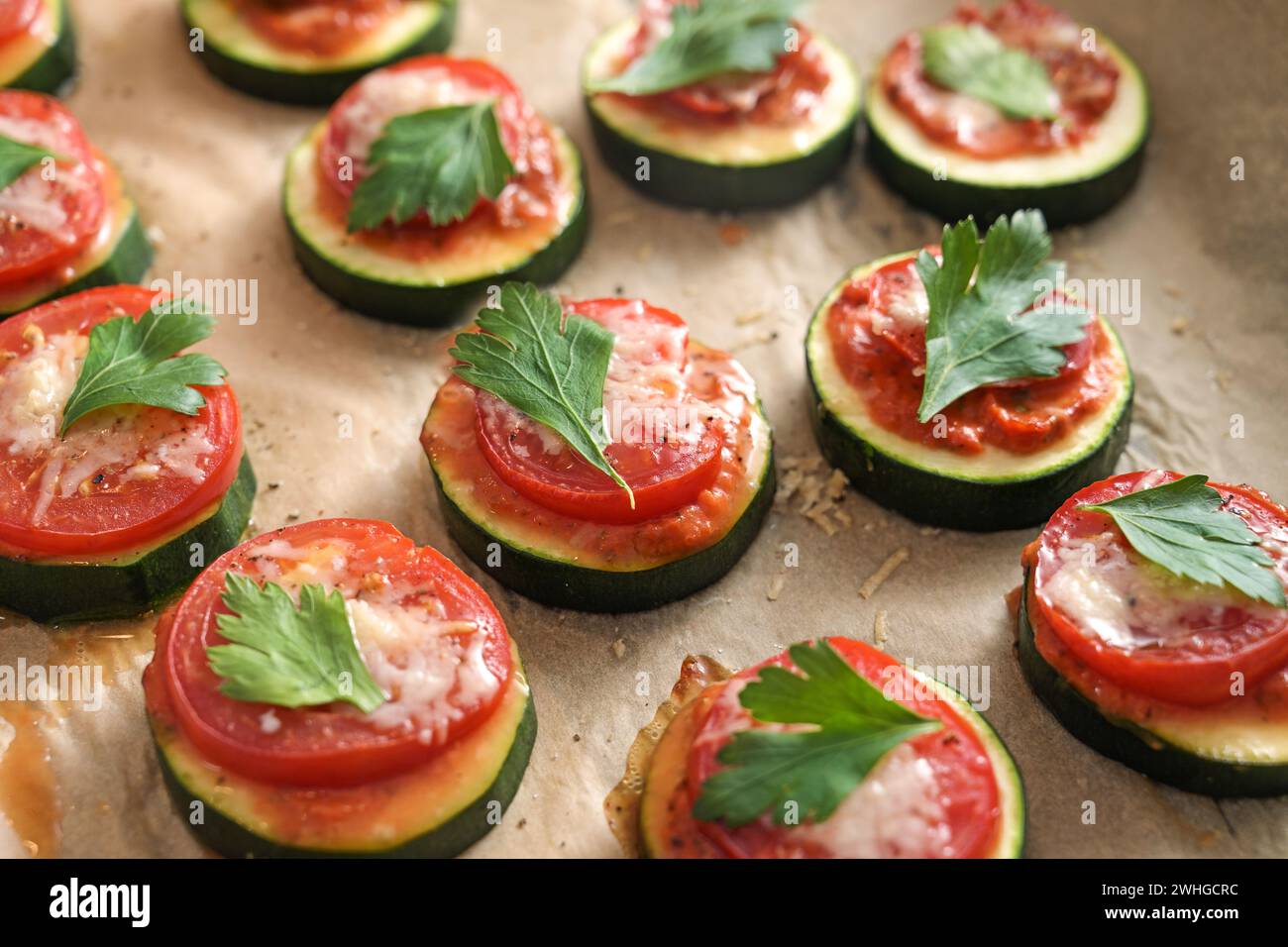 Spuntino con zucchine al forno con pomodoro, formaggio e guarnigione di prezzemolo, mini pizza vegetariana per una sana dieta a basso contenuto di carboidrati, primo piano Foto Stock