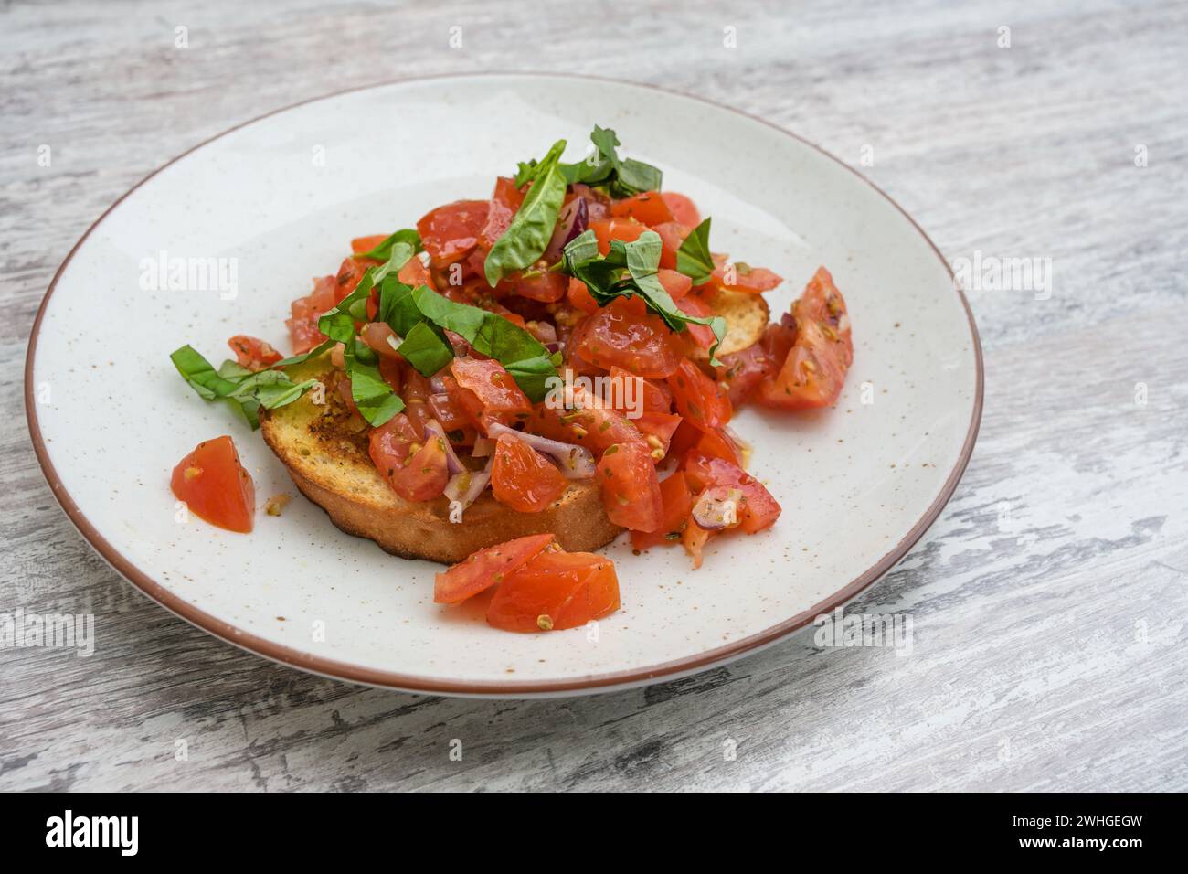 Bruschetta, pane tostato con aglio e olio d'oliva, servito con pomodori a dadini, cipolla e basilico, popolare antipasto italiano su una Foto Stock