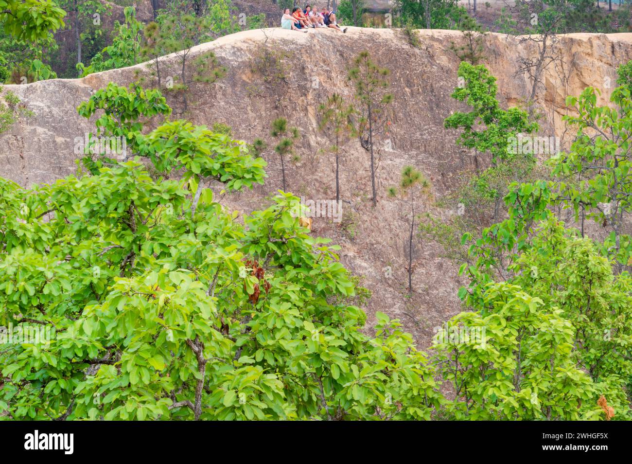 PAI, Mae Hong Son, Thailandia - 9 aprile 2023: Giovani viaggiatori arroccati in cima a un lontano precipizio, in questo paesaggio erboso e naturale Foto Stock