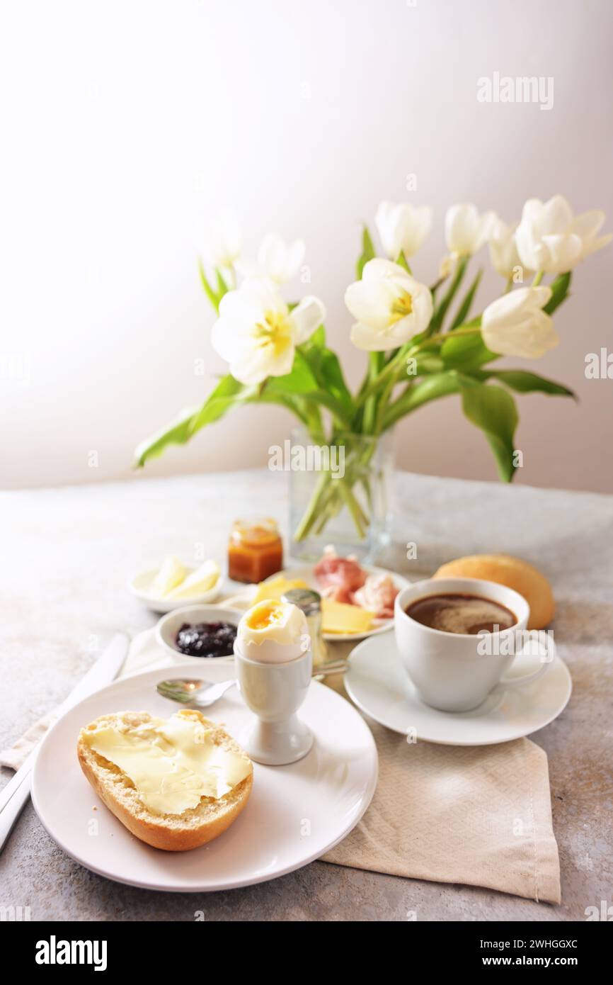 Tavolo per la colazione con fiori, panini, uova cucinate, caffè e molto altro, servito con amore la domenica, il compleanno, la festa della mamma Foto Stock